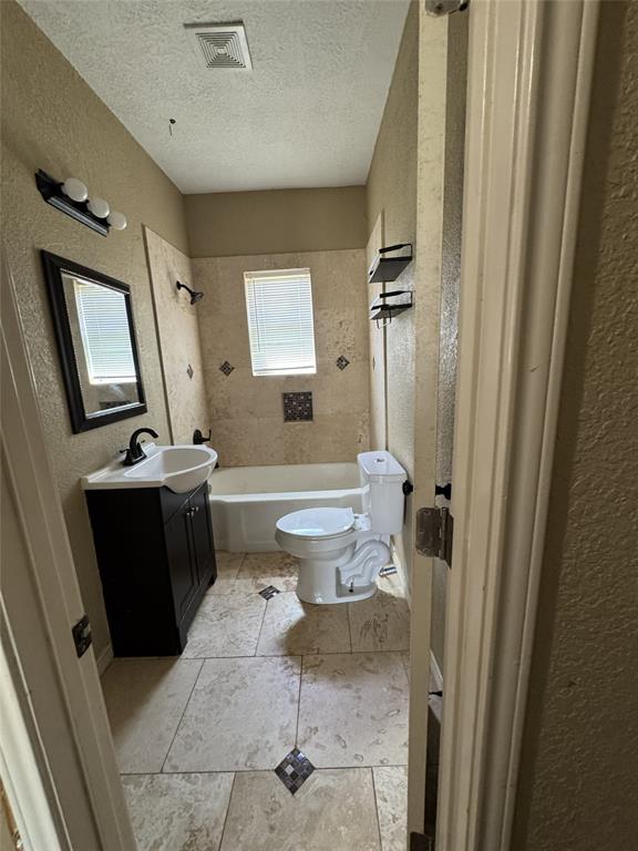 803 Ripley Avenue Ennis, TX 75119 - Photo 31 of 40 Full bathroom featuring a white tub, toilet, and a dark wood-finish vanity with a white basin sink and matte black faucet