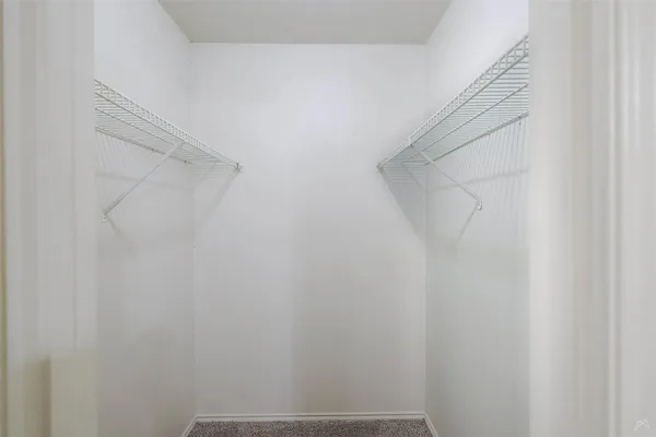 an empty room with a chandelier fan and closet area