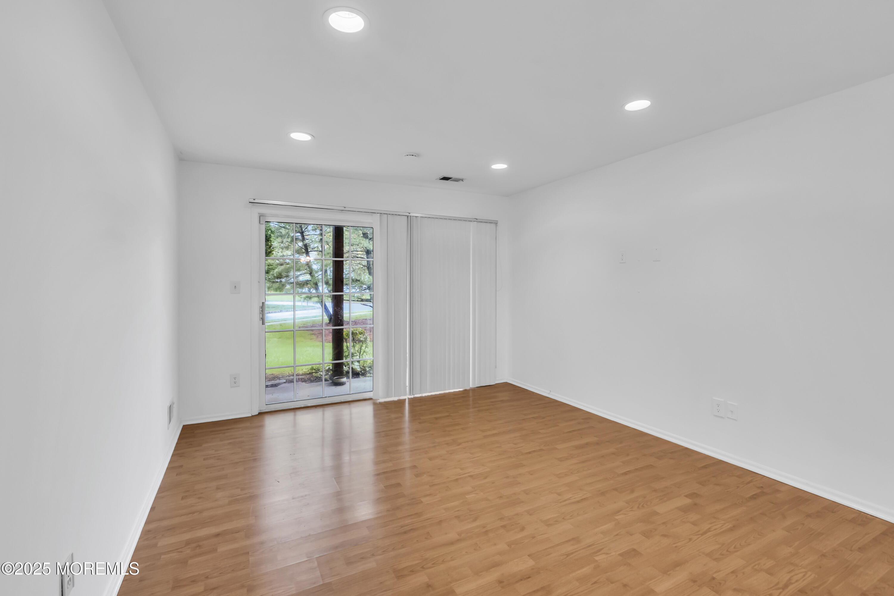 237 Paddington Court, Unit 87 Manalapan, NJ 07726 - Photo 5 of 23 a view of an empty room with wooden floor and a window