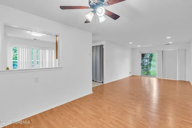 a view of an empty room with window and wooden floor