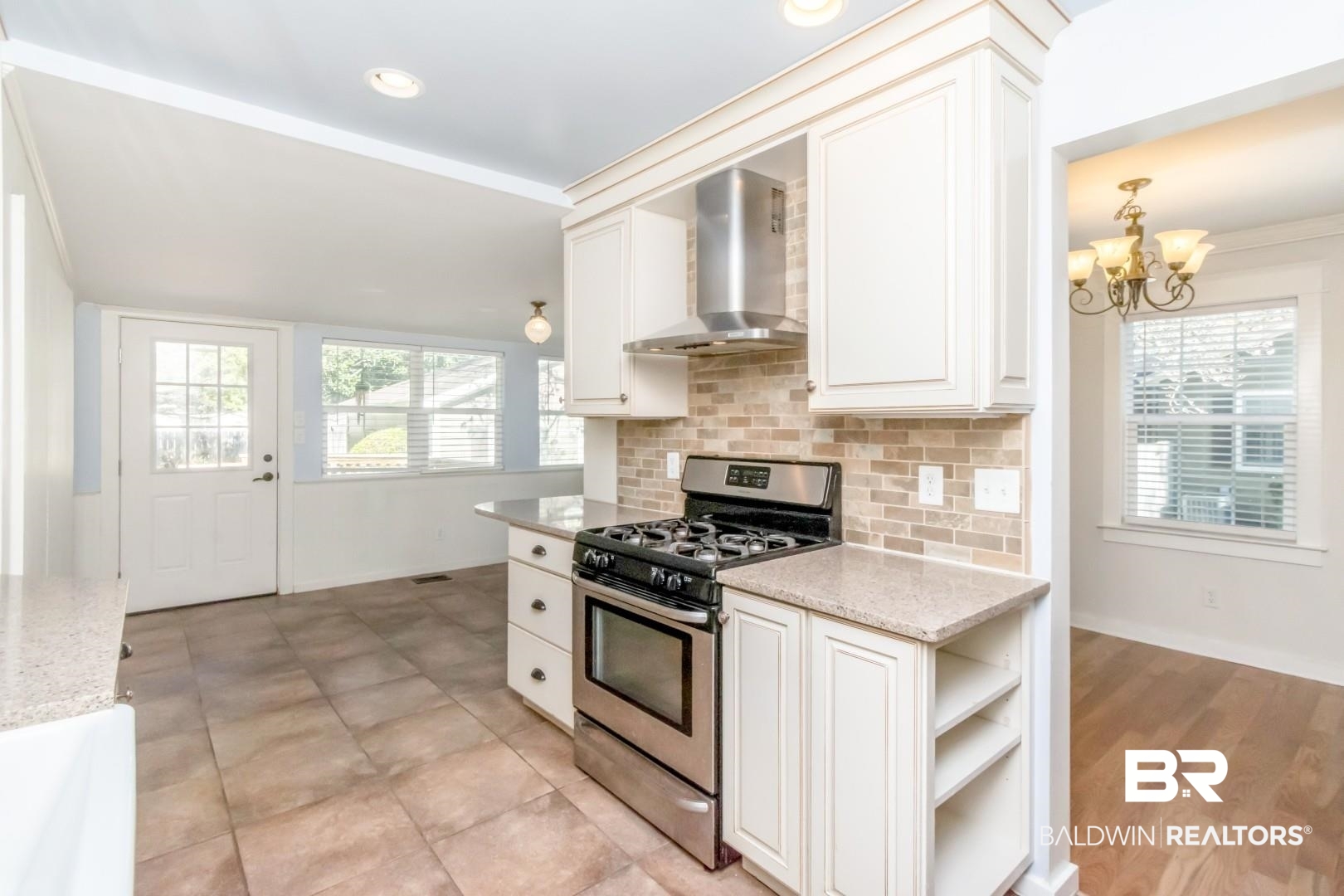 10 South Hathaway Road Mobile, AL 36608 - Photo 8 of 46 Kitchen featuring gas stove, wall chimney exhaust hood, light stone countertops, a chandelier, and decorative backsplash