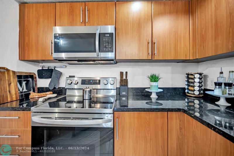 3410 Pinewalk Drive North, Unit 812 Pompano Beach, FL 33063 - Photo 8 of 26 a kitchen with stainless steel appliances granite countertop a stove a sink and a microwave