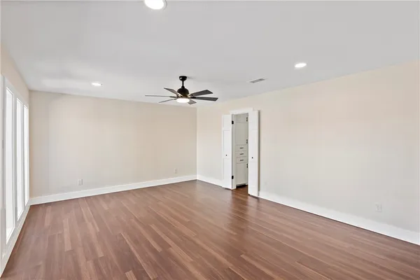 a view of empty room with wooden floor and fan