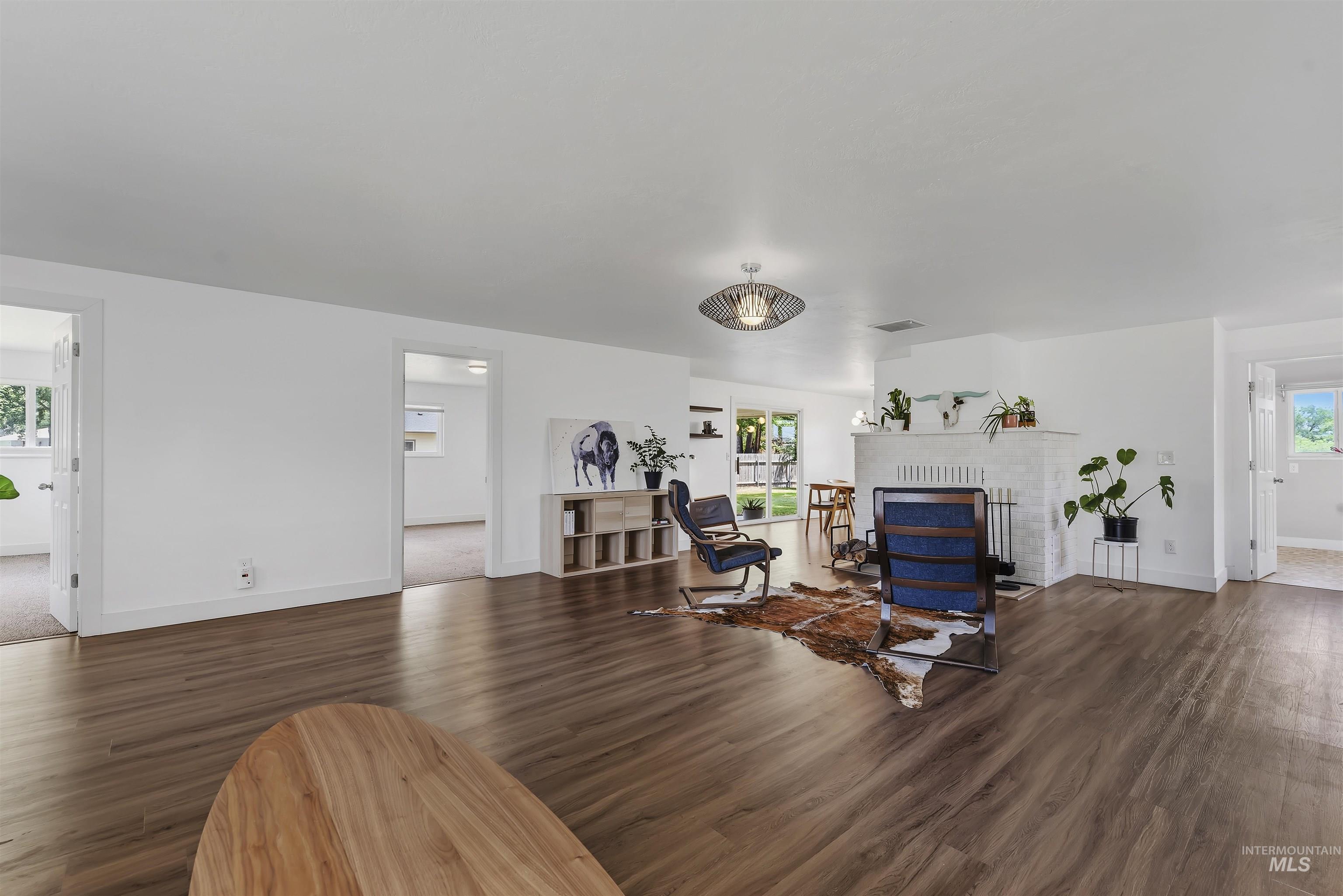 355 East Beacon Light Road Eagle, ID 83616 - Photo 9 of 47 Spacious living area featuring wood-finish flooring, white walls, and a prominent fireplace with a white brick surround