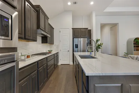a kitchen with stainless steel appliances granite countertop a kitchen island a stove a sink a refrigerator and cabinets