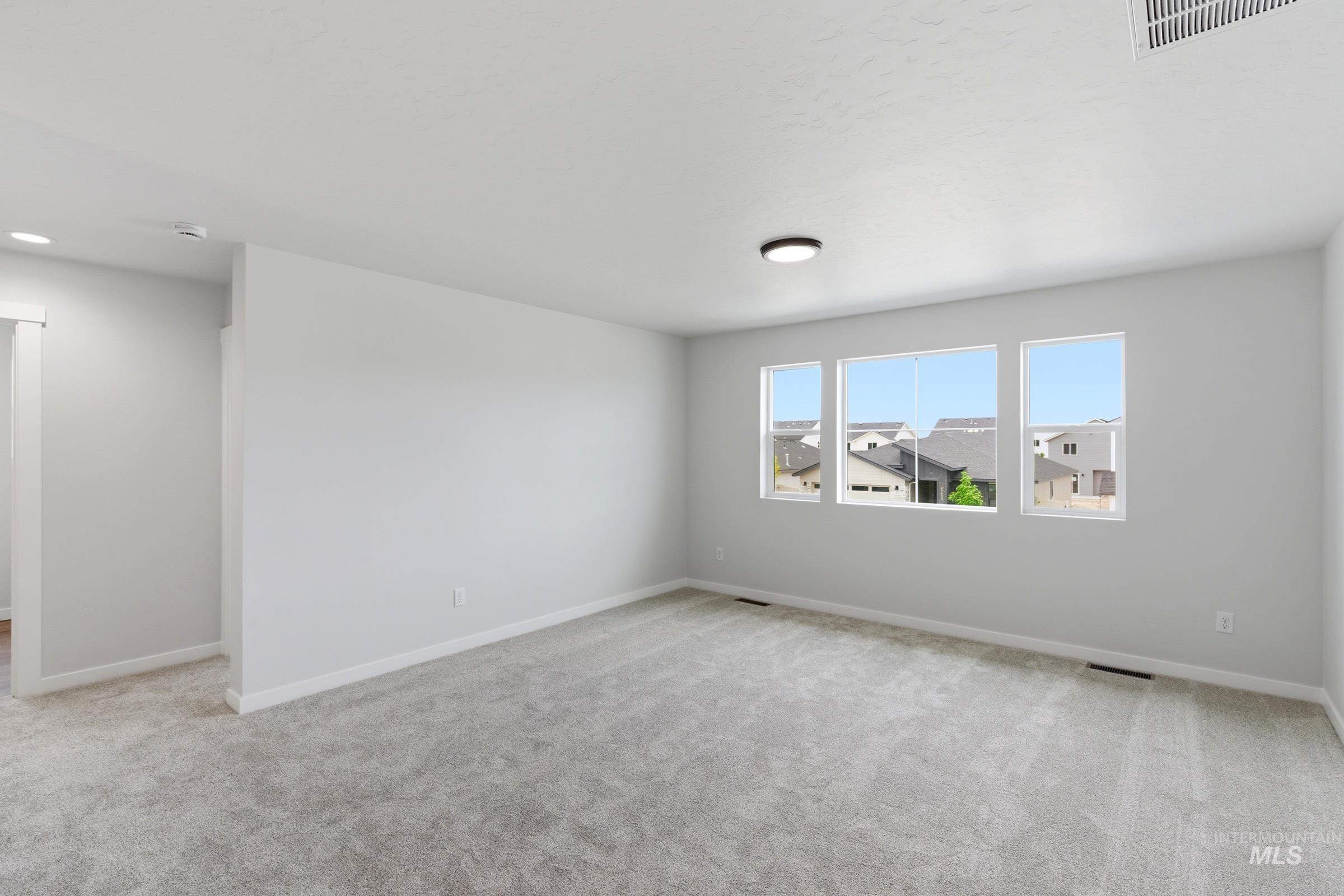 12829 Decatur Street Nampa, ID 83651 - Photo 18 of 33 Carpeted room featuring three rectangular windows, white trim, and a flush-mount ceiling light