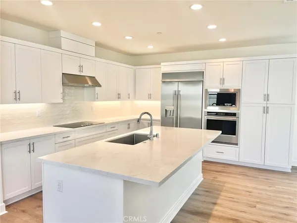 a large kitchen with stainless steel appliances kitchen island a large counter top a stove and a sink