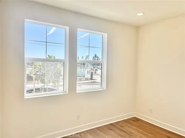 a view of an empty room with wooden floor and windows