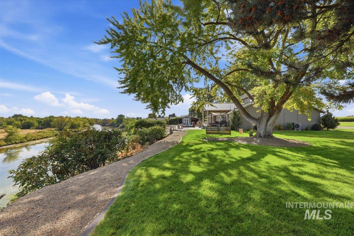 7900 Elmore Road Fruitland, ID 83619 - Photo 44 of 50 Manicured lawn with mature shade trees, gravel pathway, and waterside landscaping
