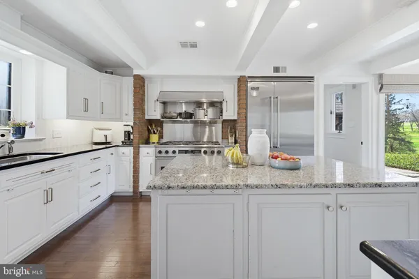 a kitchen with granite countertop a sink stainless steel appliances and white cabinets