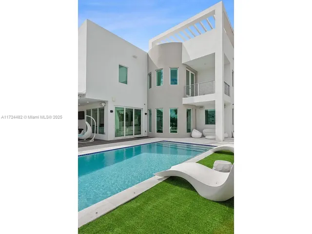 a view of a swimming pool with lawn chairs and a yard