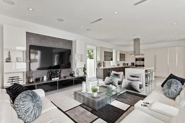 a living room with furniture a flat screen tv and kitchen view