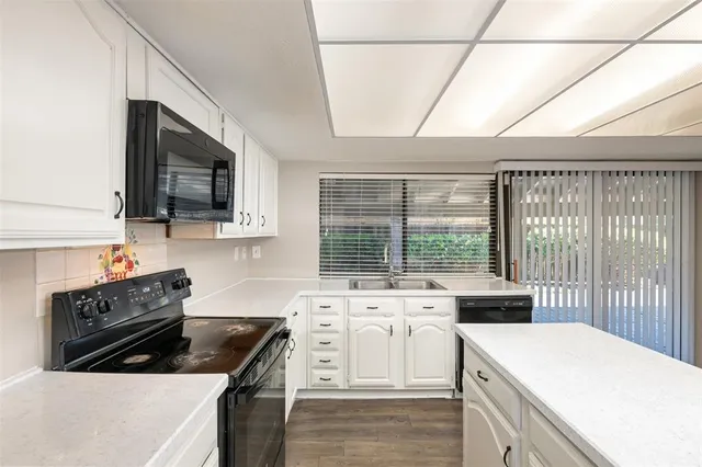 a kitchen that has a sink a stove and a microwave oven in a cabinets