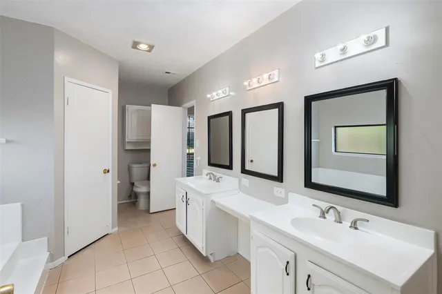 a bathroom with a double vanity sink mirror and toilet