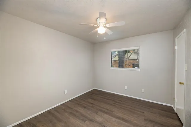 an empty room with wooden floor chandelier fan and windows