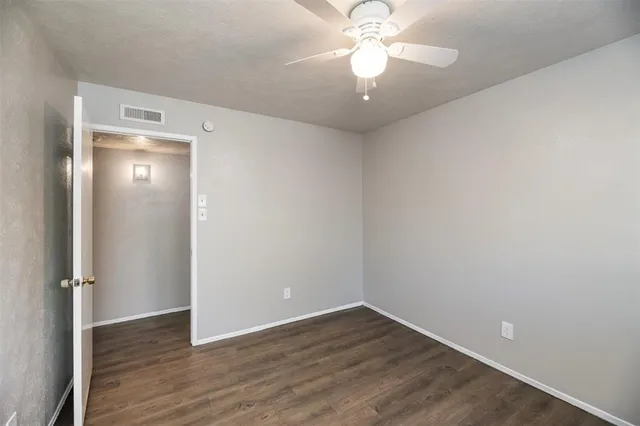 an empty room with wooden floor and a ceiling fan