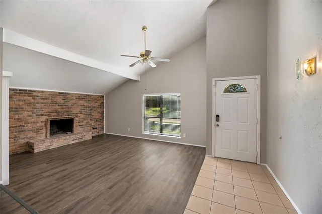 an empty room with wooden floor fireplace and windows