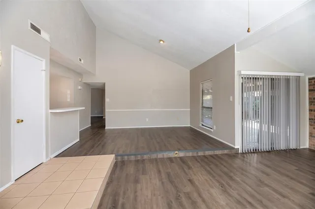 a view of a hallway with wooden floor and a refrigerator