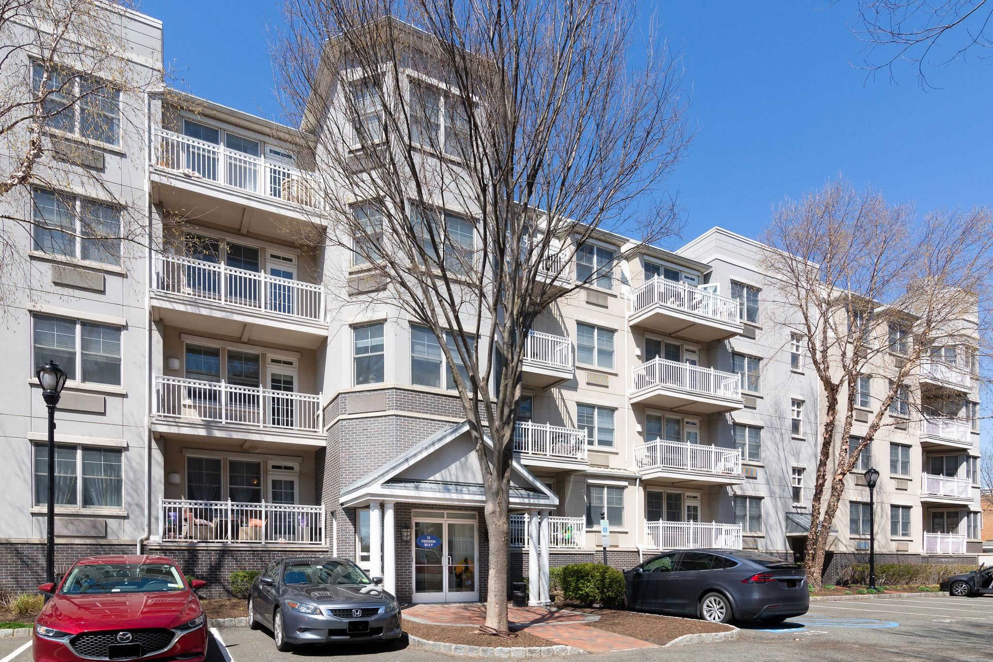 a front view of a building with lot of cars and trees