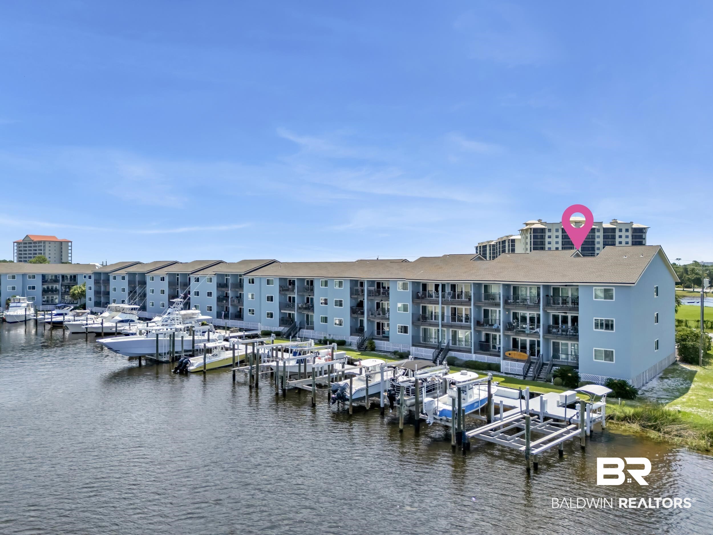 14100 River Road, Unit 211 Pensacola, FL 32507 - Photo 49 of 56 Waterfront multi-story building featuring individual boat slips, private balconies, and a clear blue sky overhead