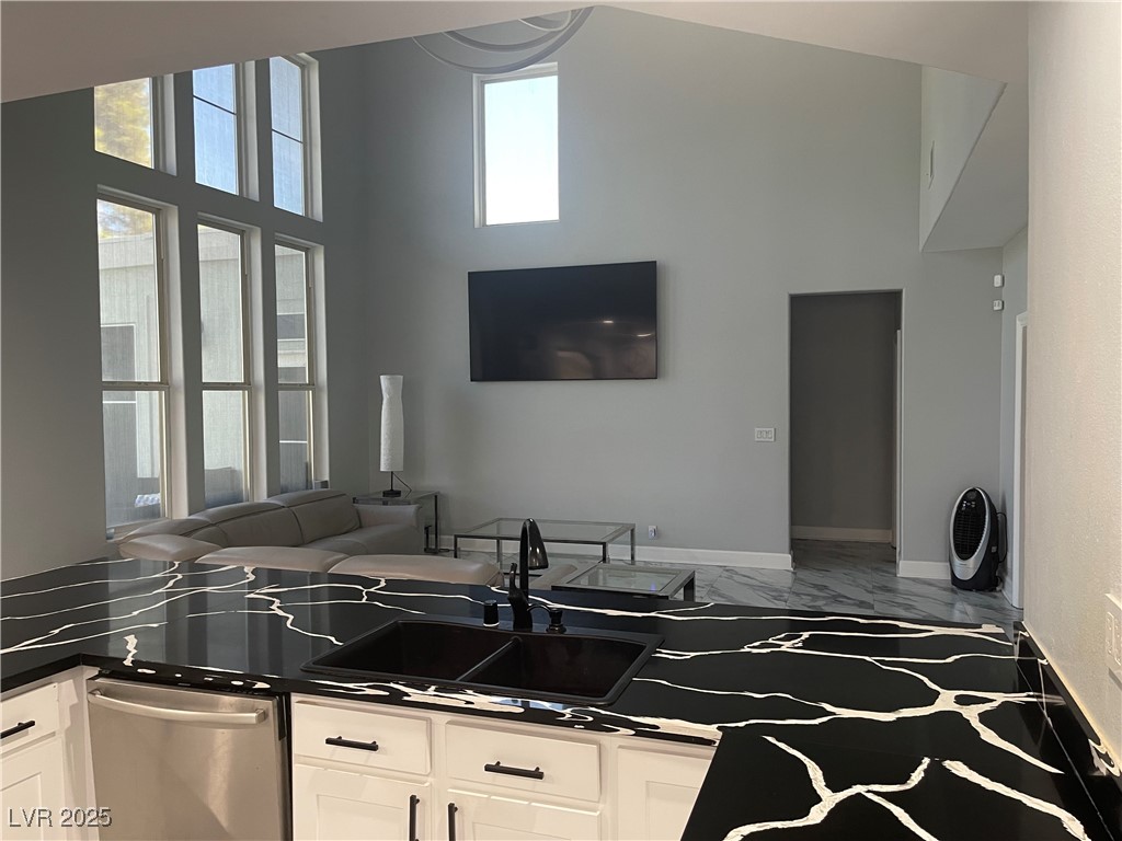 6480 West Oquendo Road Las Vegas, NV 89118 - Photo 51 of 51 Kitchen with white cabinets, stainless steel dishwasher, a high ceiling, open floor plan, and marble finish floors