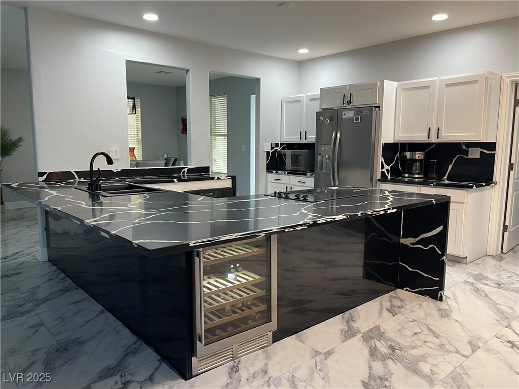 6480 West Oquendo Road Las Vegas, NV 89118 - Photo 12 of 51 Kitchen featuring light marble finish flooring, a peninsula, dark countertops, stainless steel fridge with ice dispenser, and beverage cooler