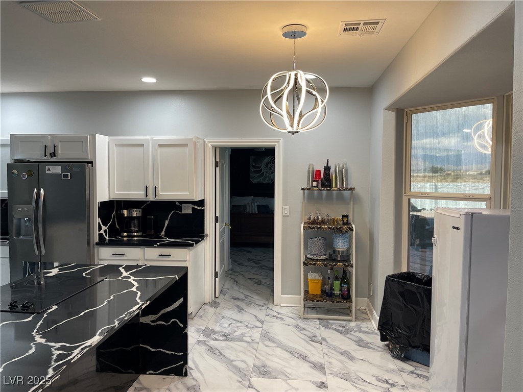 6480 West Oquendo Road Las Vegas, NV 89118 - Photo 14 of 51 Kitchen with stainless steel fridge, light marble finish flooring, decorative light fixtures, a chandelier, and white cabinets