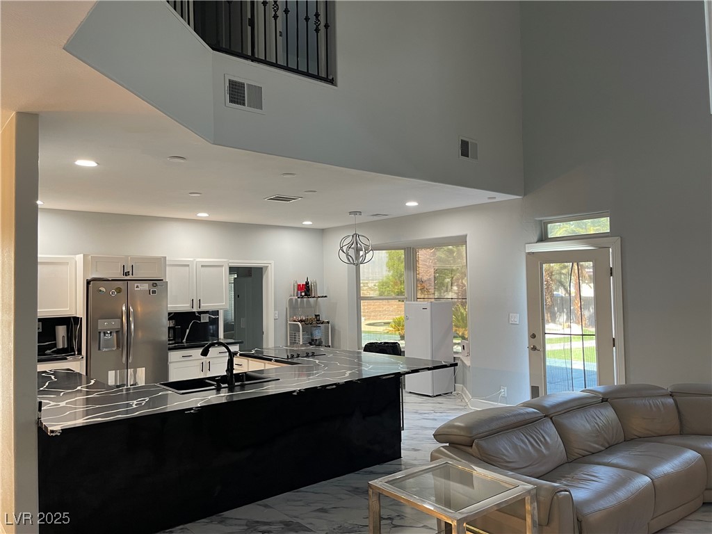6480 West Oquendo Road Las Vegas, NV 89118 - Photo 17 of 51 Kitchen featuring stainless steel fridge with ice dispenser, decorative light fixtures, white cabinetry, dark countertops, and recessed lighting