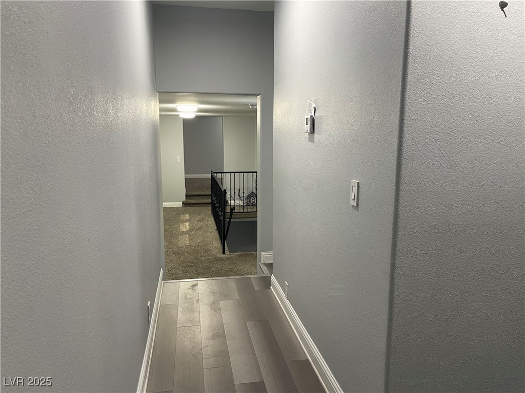 6480 West Oquendo Road Las Vegas, NV 89118 - Photo 29 of 51 Hallway downstairs with a textured wall, dark wood finished floors, and an upstairs landing