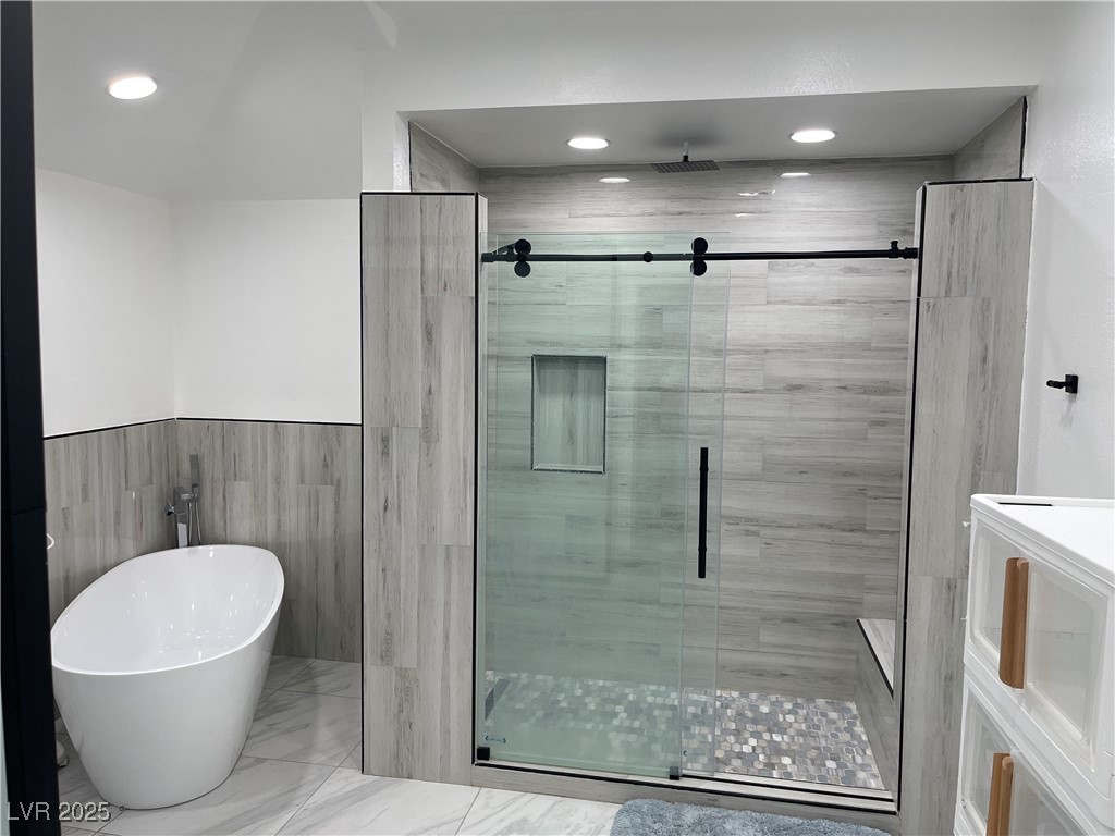 6480 West Oquendo Road Las Vegas, NV 89118 - Photo 43 of 51 Full bathroom featuring a stall shower, a freestanding bath, recessed lighting, marble finish floors, and a wainscoted wall