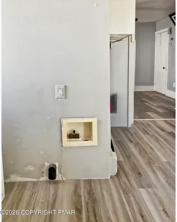 a view of a hallway with wooden floor and a cabinet