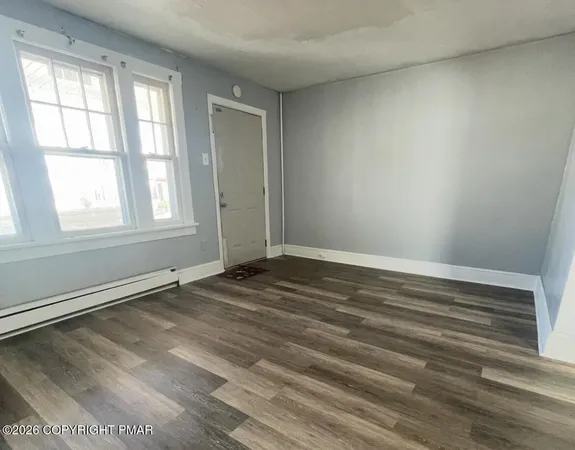 an empty room with wooden floor and windows