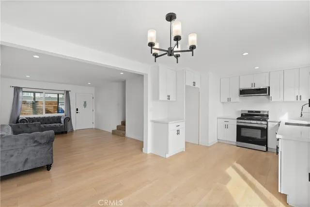 a view of kitchen with stainless steel appliances refrigerator stove microwave and living room