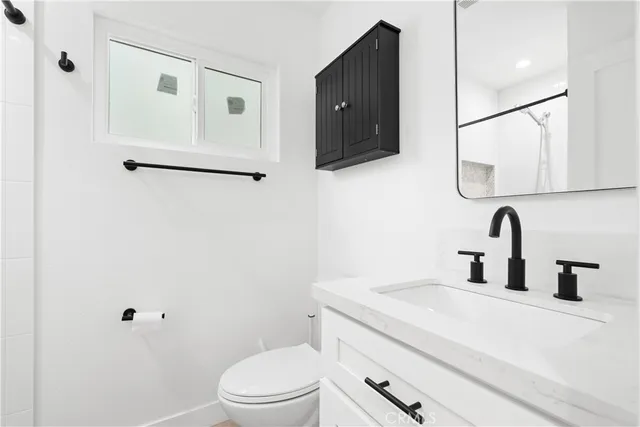 a bathroom with a toilet sink vanity and mirror