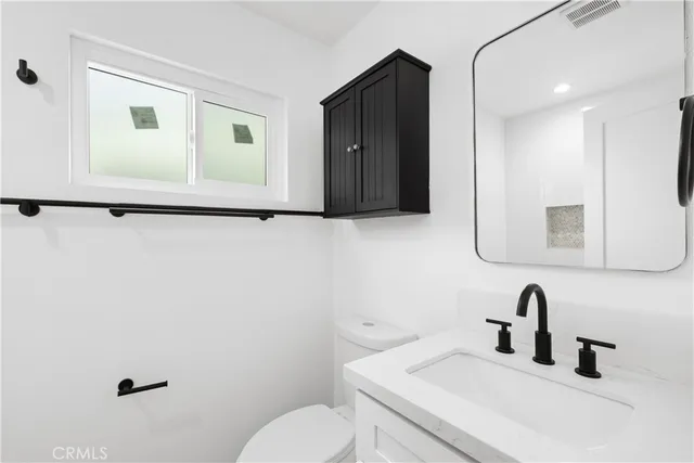 a bathroom with a toilet sink vanity and mirror