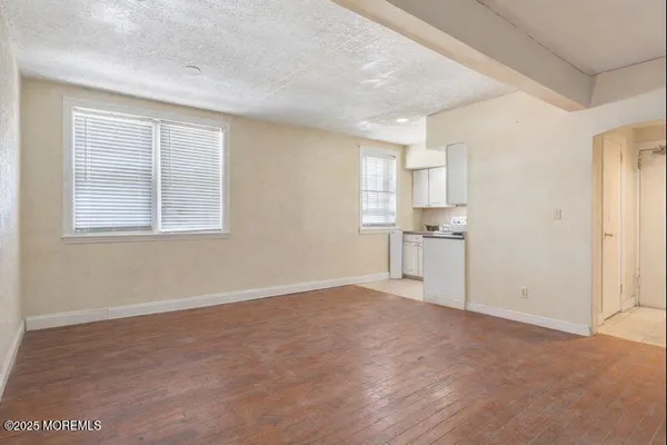a view of an empty room with window and wooden floor
