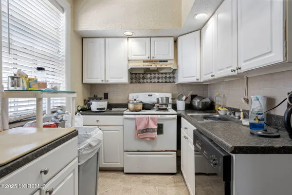 a kitchen with granite countertop white cabinets and white appliances