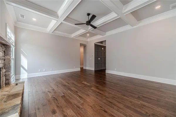 a view of a livingroom with wooden floor a ceiling fan and windows