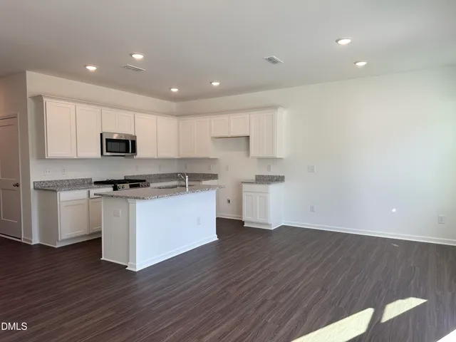 a kitchen with granite countertop white cabinets and stainless steel appliances