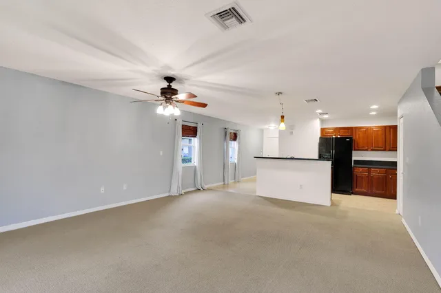 an empty room with a kitchen and a ceiling fan