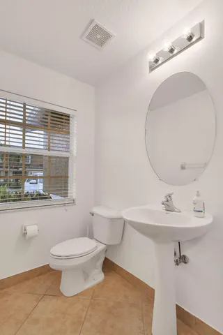 a bathroom with a toilet sink a mirror and window