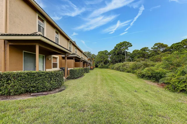 a yellow house with a big yard and large trees