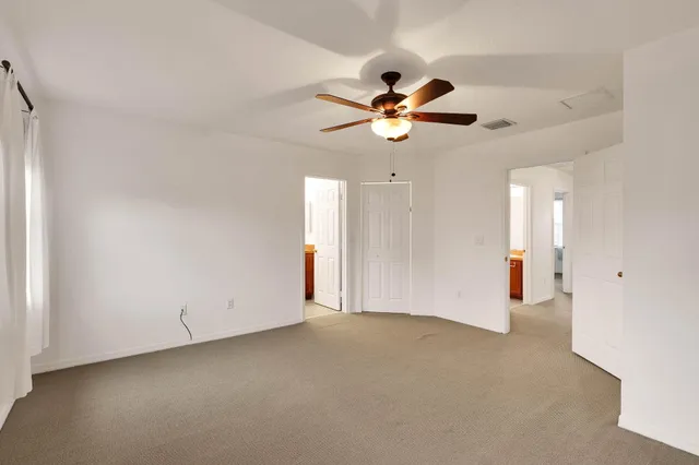 an empty room with closet and a chandelier fan