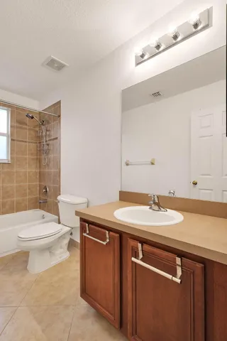 a bathroom with a granite countertop toilet sink mirror and shower
