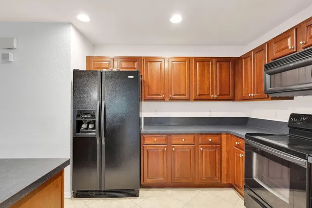 a kitchen with stainless steel appliances granite countertop a refrigerator a stove and a sink with wooden cabinets