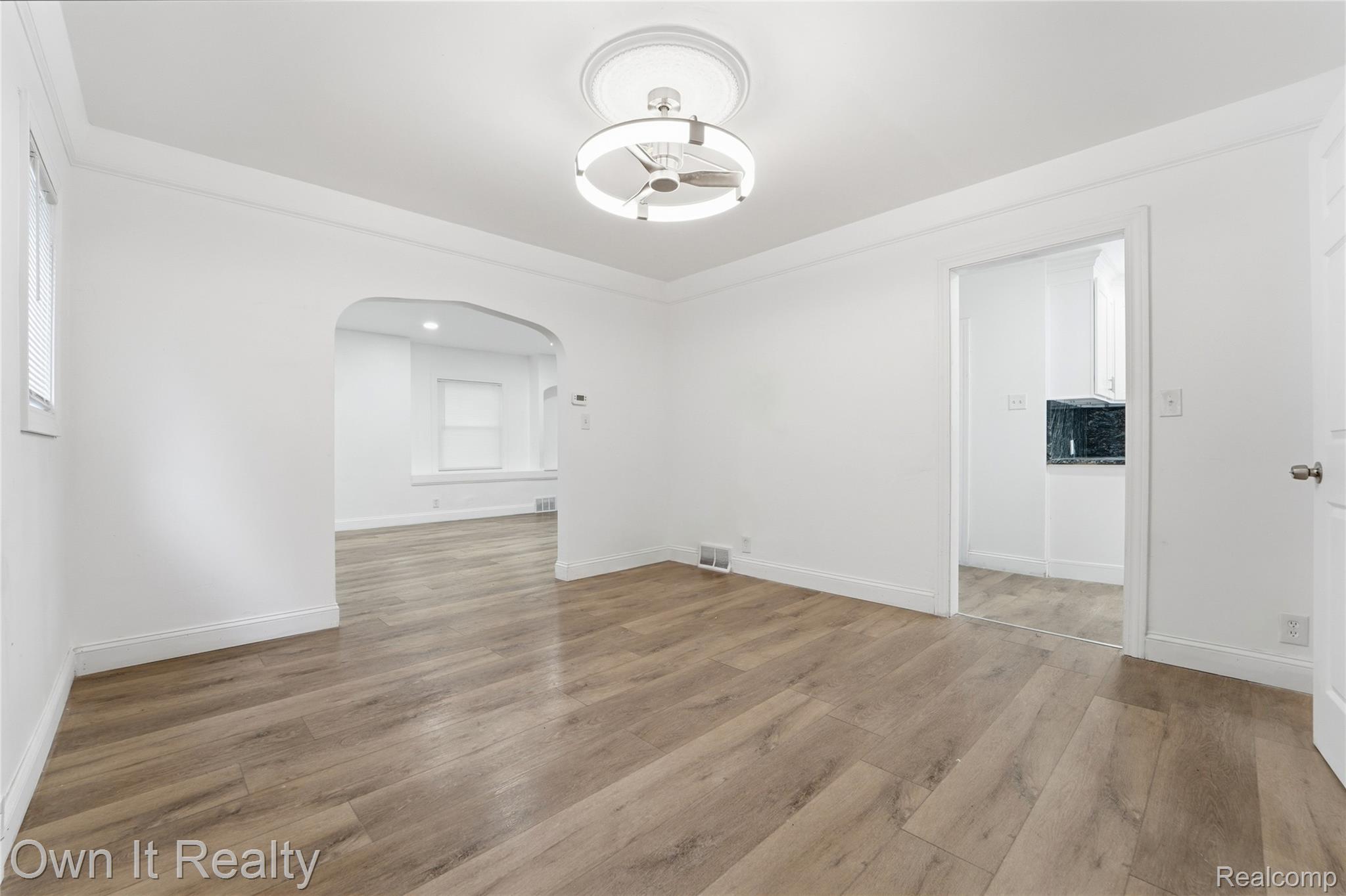 17351 Appoline Street Detroit, MI 48235 - Photo 22 of 34 Spacious interior featuring wood-finish flooring, white painted walls, a modern ceiling light fixture, an arched doorway, and white baseboards