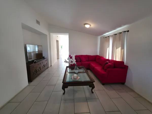 a view of a dining room and livingroom with furniture a rug a rug and a window