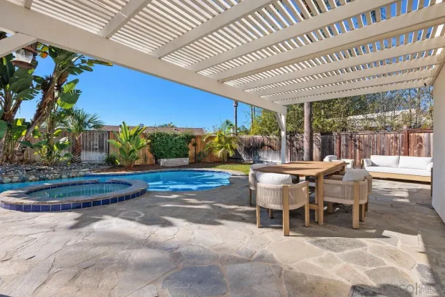a view of a patio with table and chairs potted plants and floor to ceiling window
