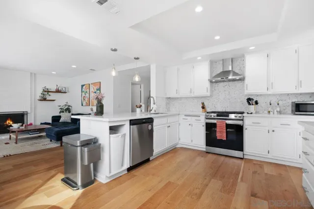 a kitchen with stainless steel appliances a stove top oven a sink dishwasher and a refrigerator with wooden floor