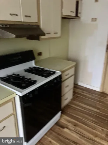 a kitchen with granite countertop a sink and a stove with wooden floor